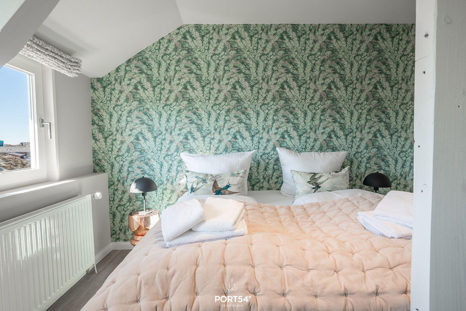 Bedroom with patterned wall, bed, and window.