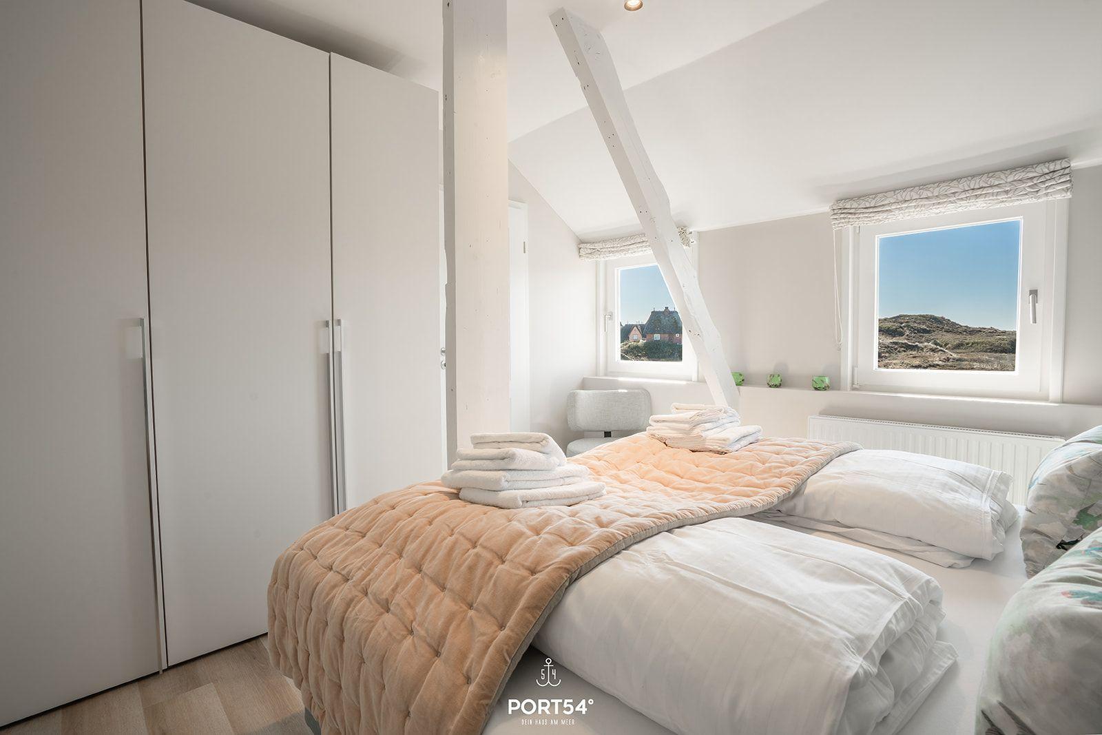Bedroom with double bed, white walls, and window view of landscape.