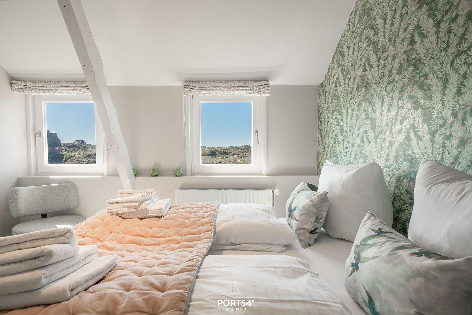 Bedroom with view of the landscape, comfortable bed and patterned wallpaper.