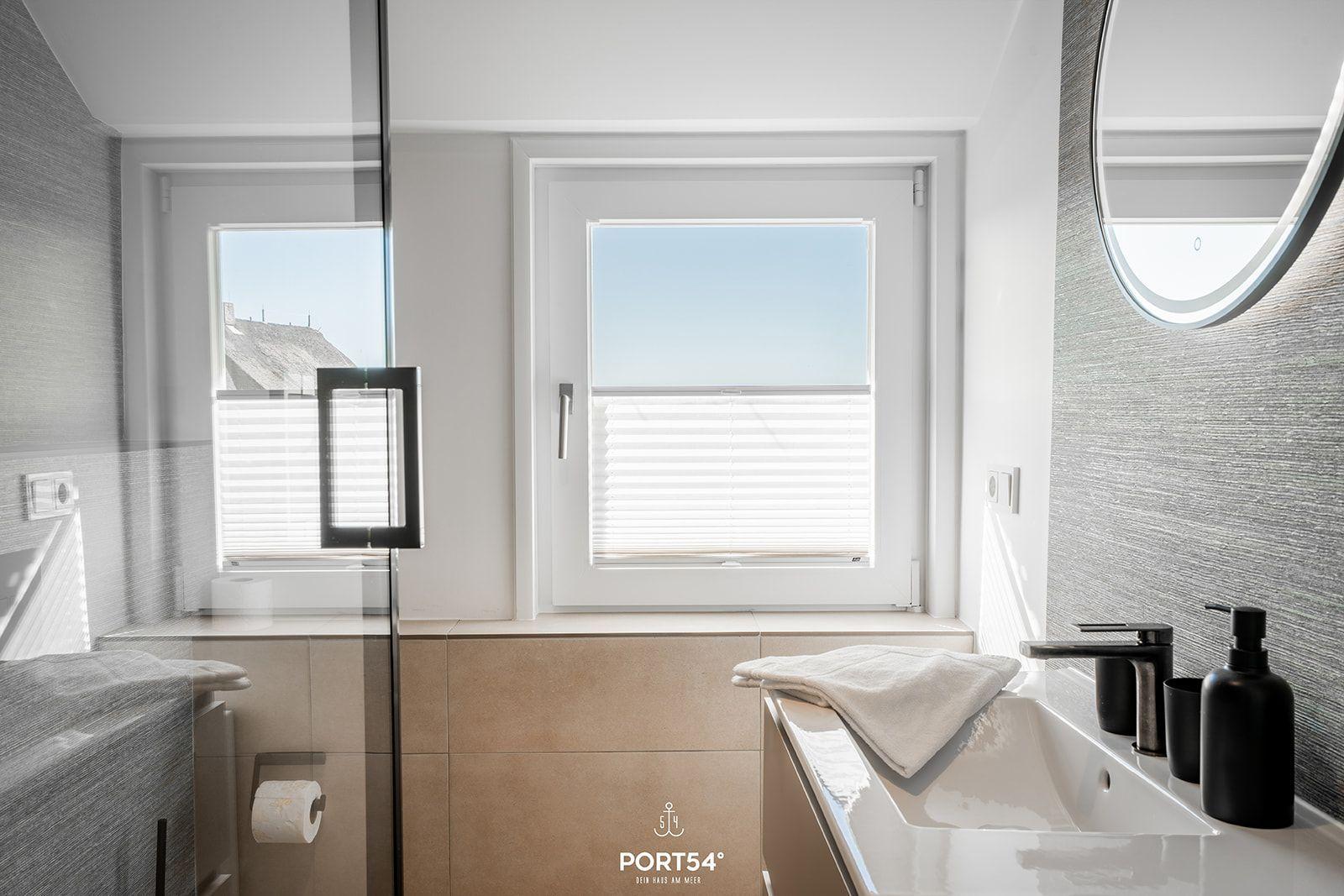 Bathroom with window, sink, and mirror.