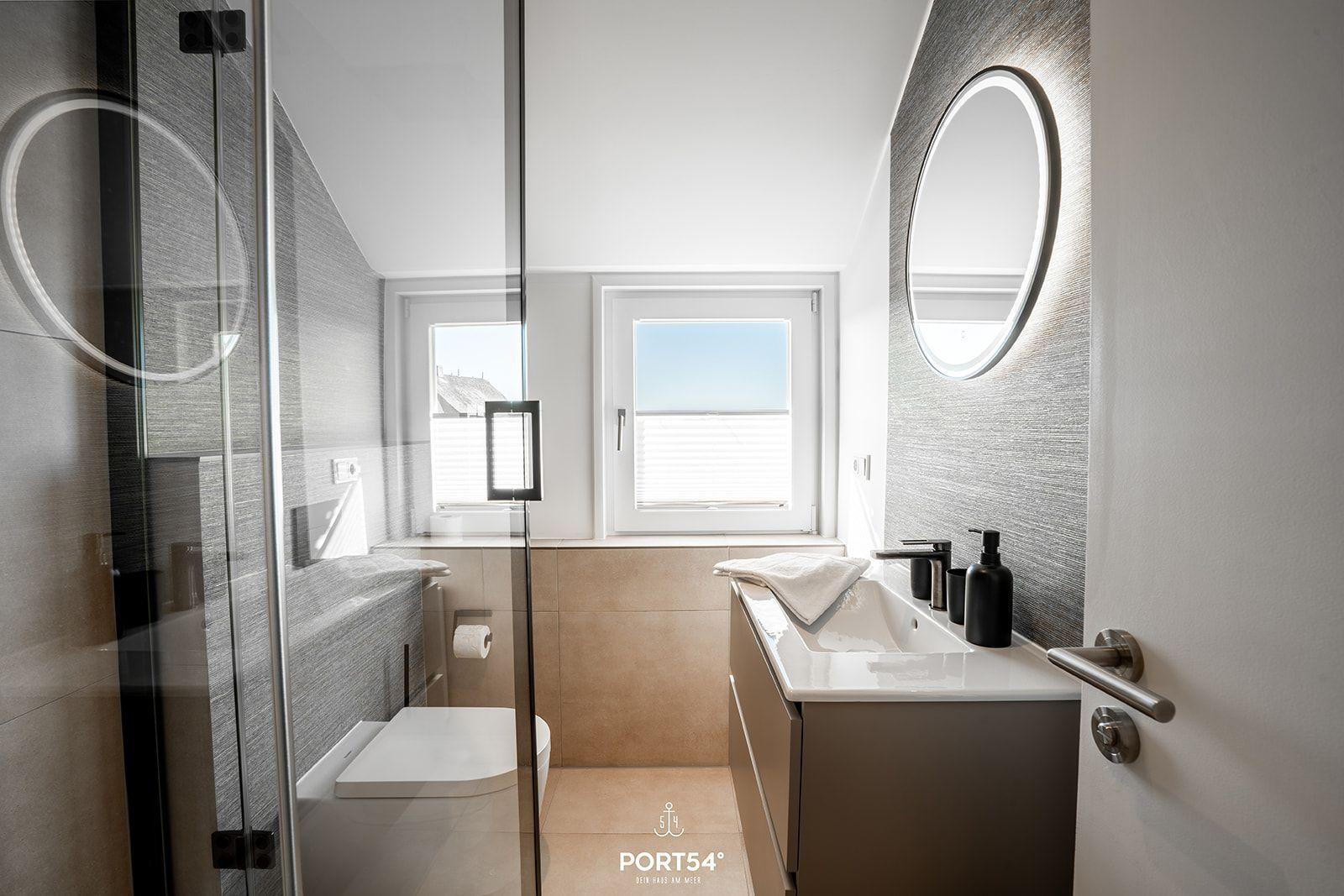 Modern bathroom with shower, sink, and window with sea view.