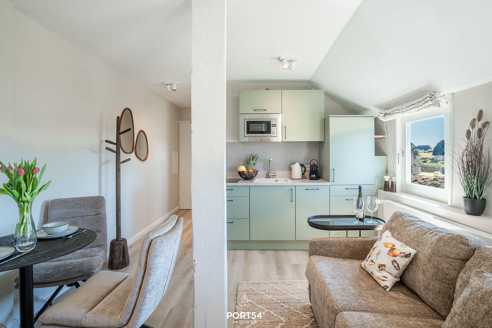 Living area with sofa, kitchenette, and dining space. Window view of landscape.