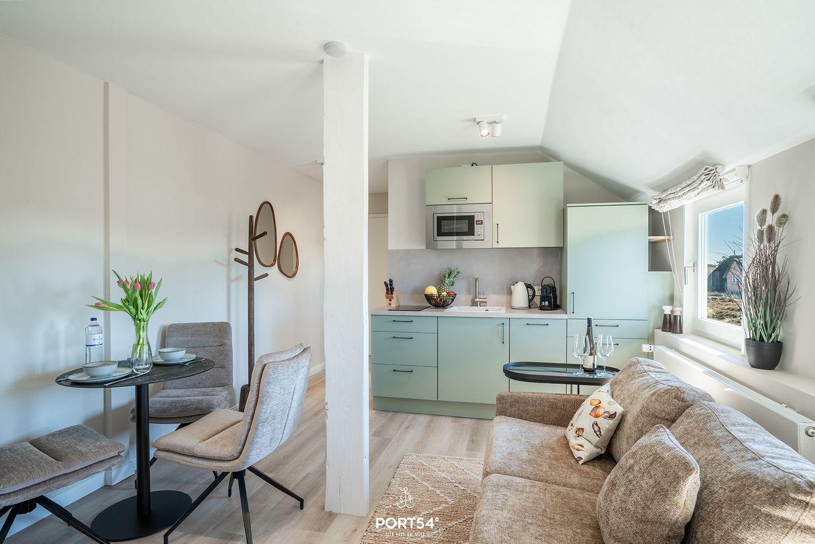Living and kitchen area with sofa, dining table, and kitchenette.