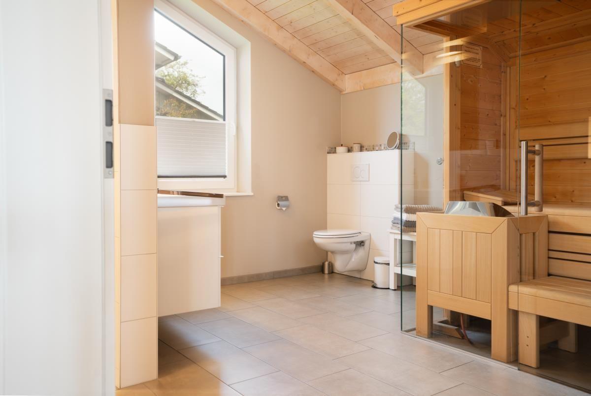 Badezimmer mit Toilette, Waschbecken und Sauna im Holzdesign.