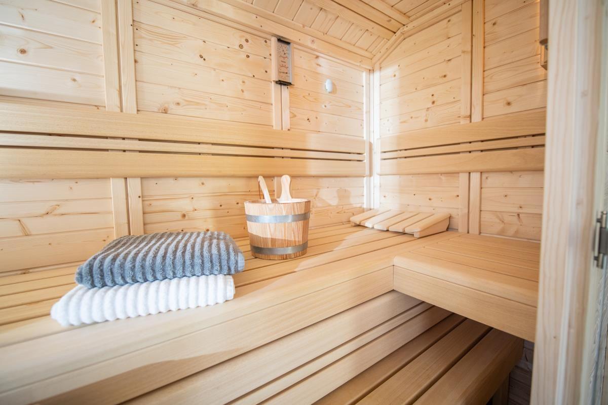 Sauna mit Holzbänken, Handtuch und Eimer.