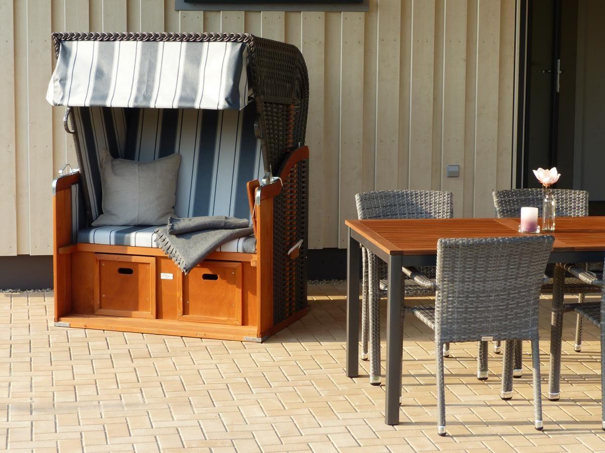 Terrasse mit Liegestuhl und Esstisch mit Stühlen.