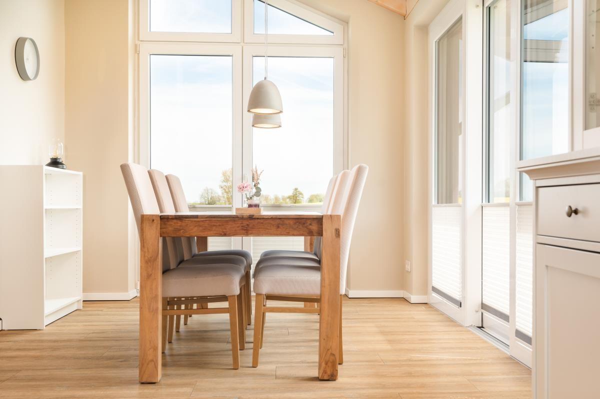 Esszimmer mit Holztisch, Stühlen und großem Fenster zur Aussicht.