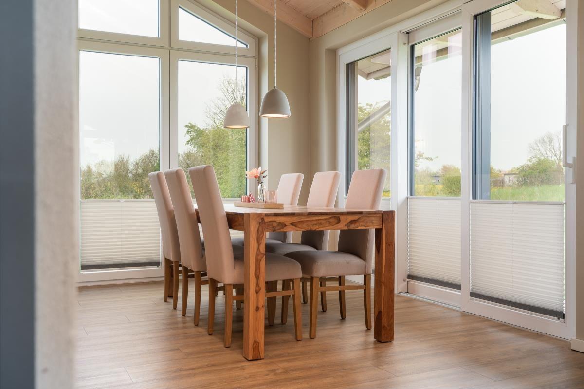 Esszimmer mit Holztisch, sechs Stühlen und großen Fenstern zur Aussicht.