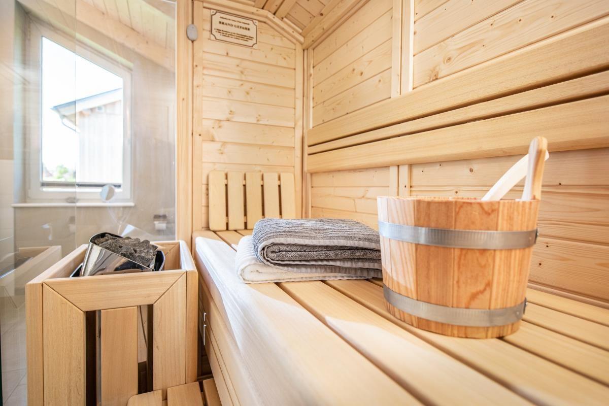 Sauna mit Holzbänken, Eimer und Handtuch. Fenster zur Außenseite.