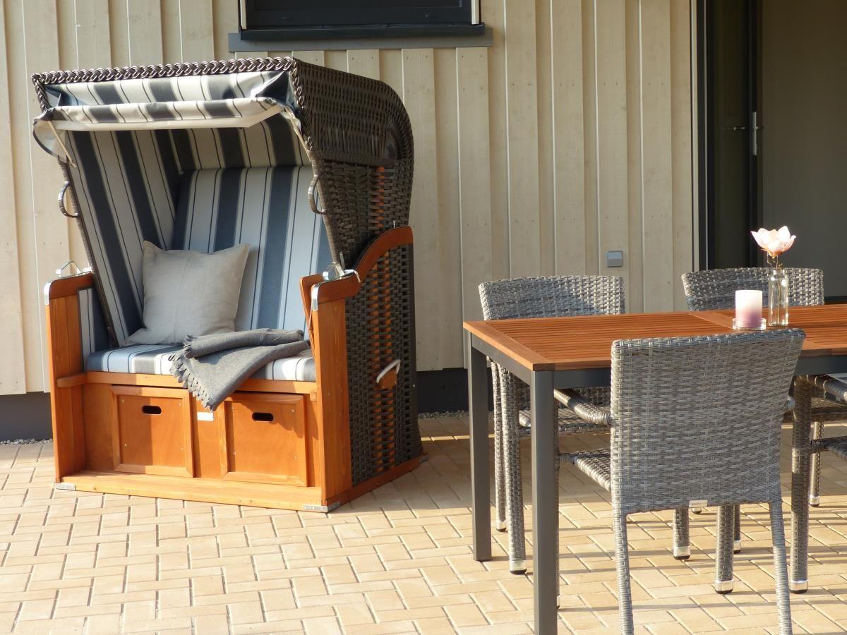 Terrasse mit Liegestuhl und Esstisch mit Stühlen.
