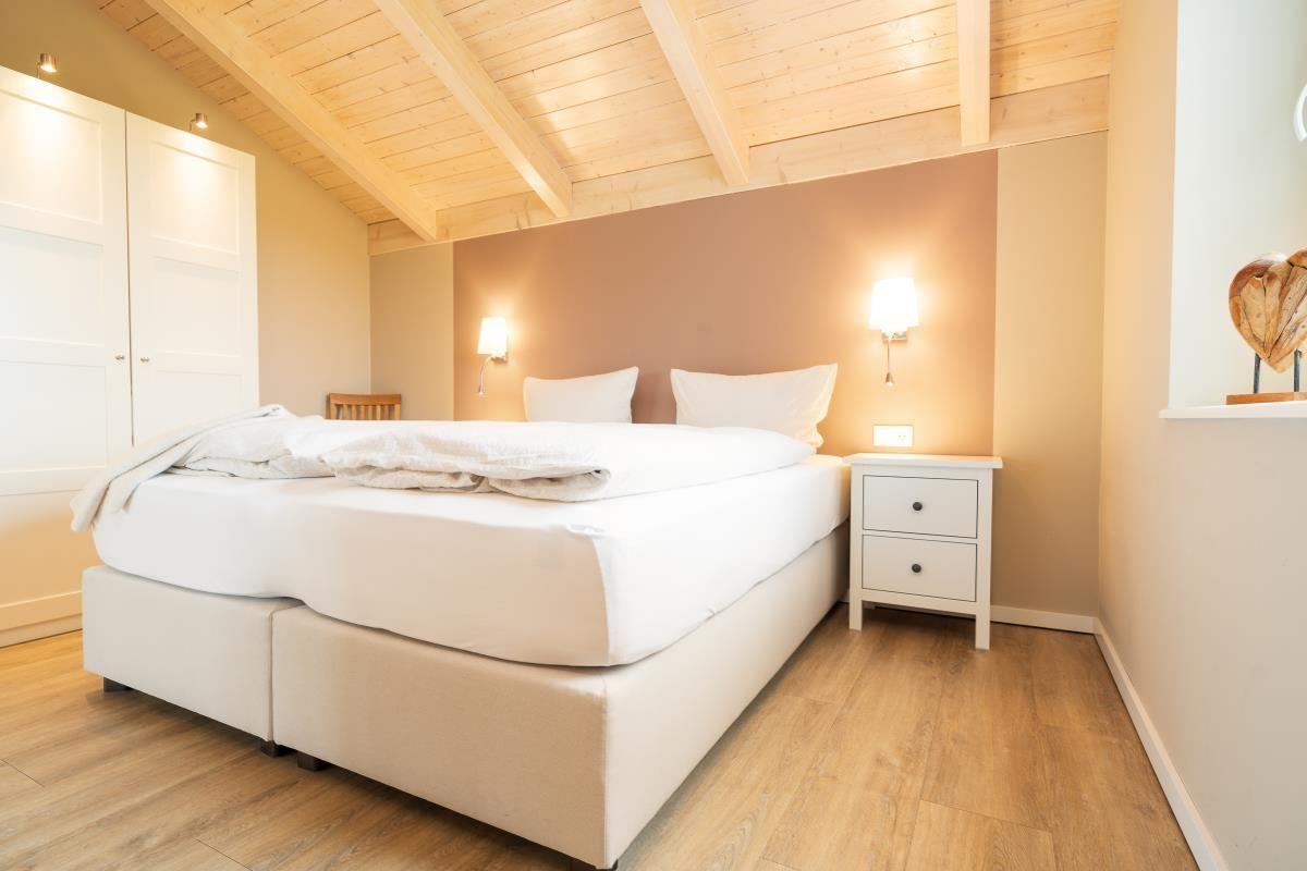 Schlafzimmer mit Doppelbett, Nachttisch und Holzdecke.