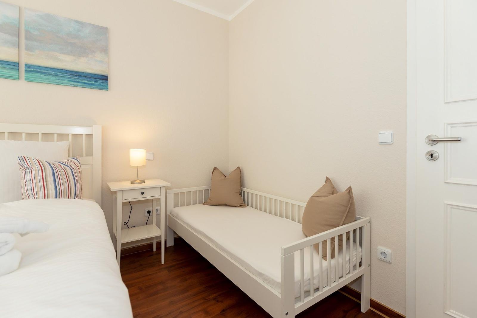Zimmer mit Bett, Schlafcouch, Nachttisch und Wandbild.