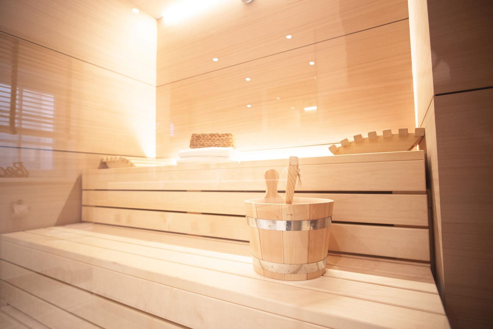Sauna mit Holzbank und Eimer mit Besen.
