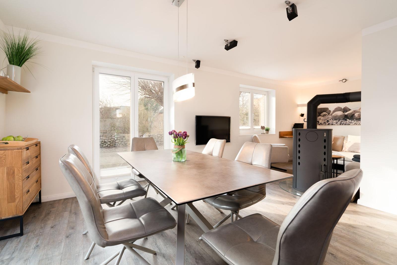 Dining area with table and chairs, TV, and fireplace in the background.