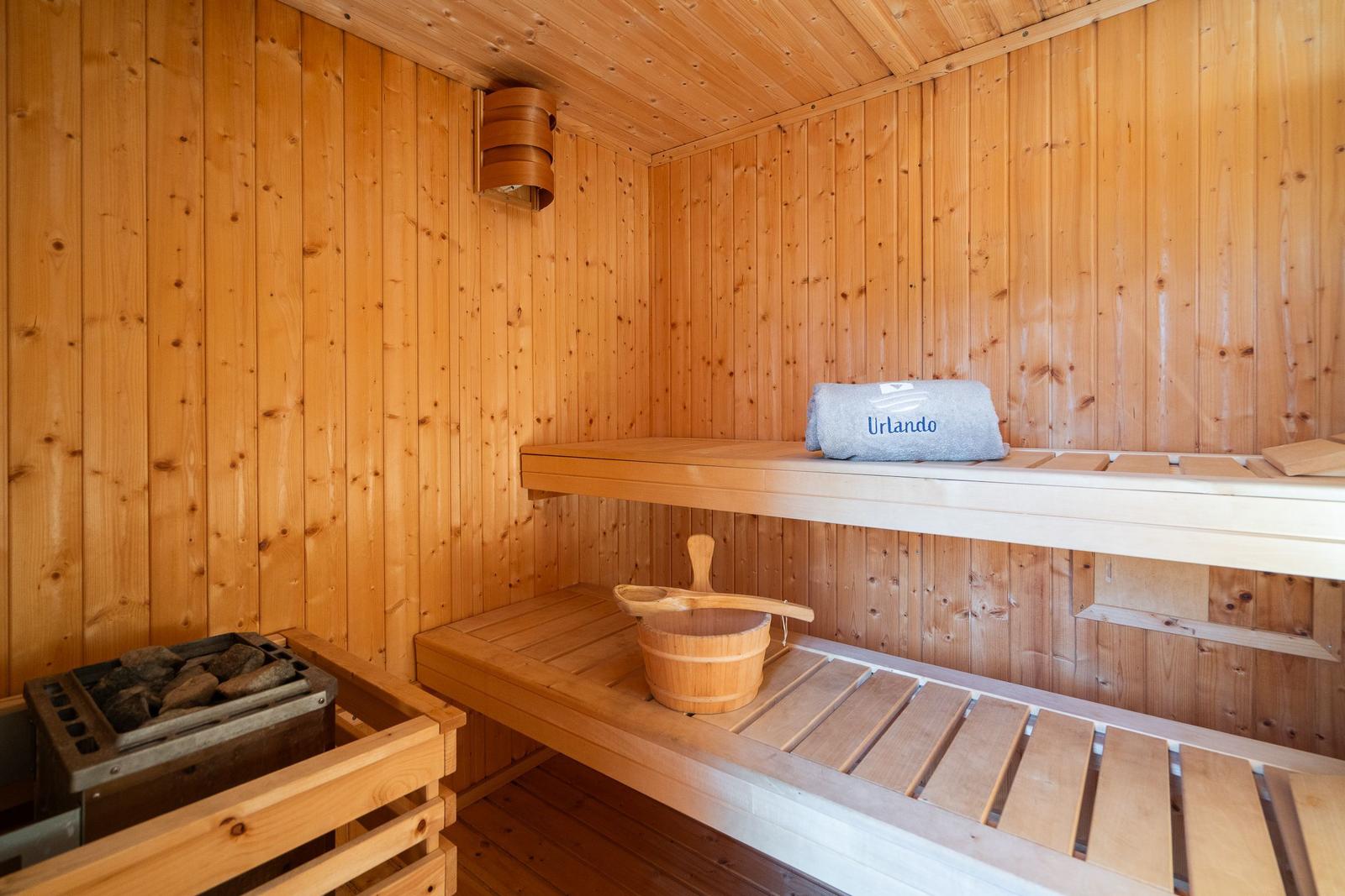 Sauna with wooden bench, bucket, and towel. Wooden walls and ceiling.