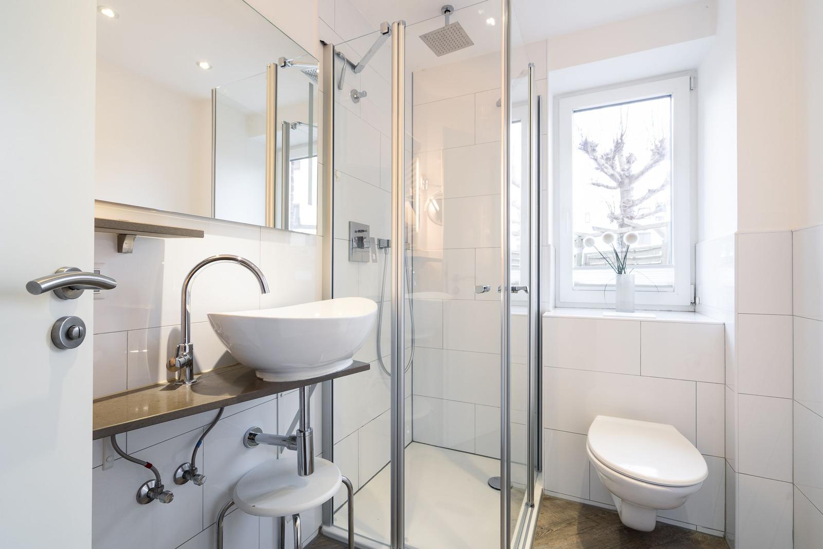 Bathroom with shower, sink, and toilet. Window with view outside.