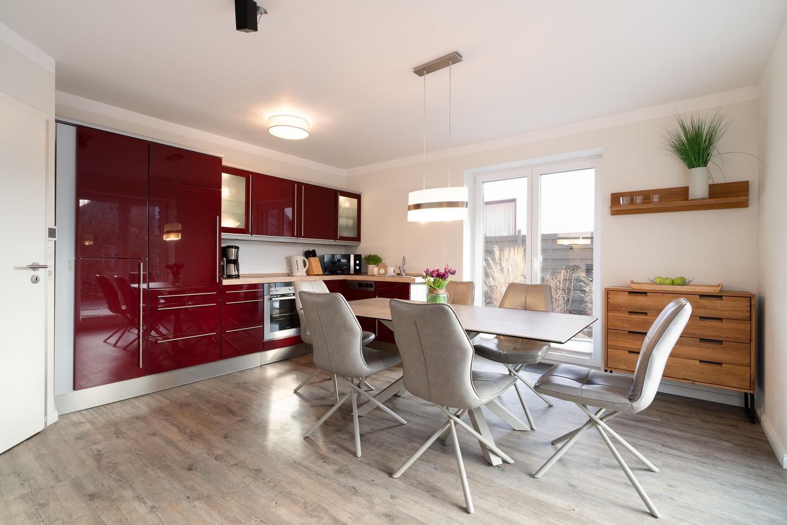 Kitchen with red cabinets and dining area with table and chairs.