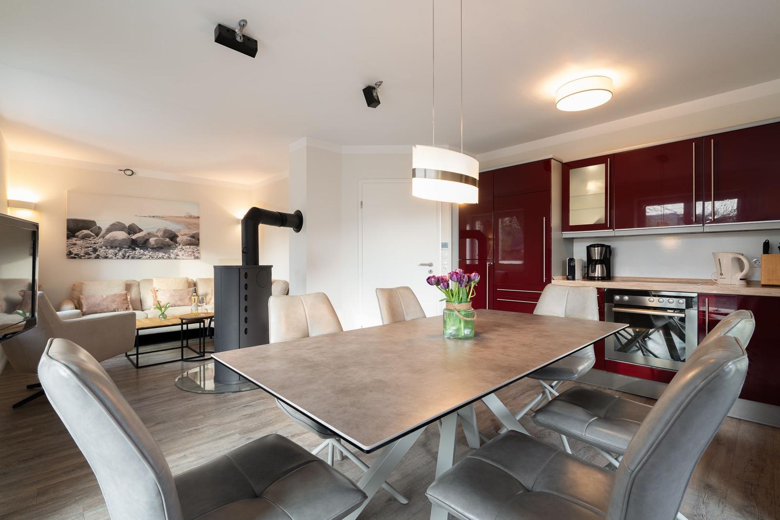 Dining area with table and chairs, kitchen with red cabinets, and living area in background.