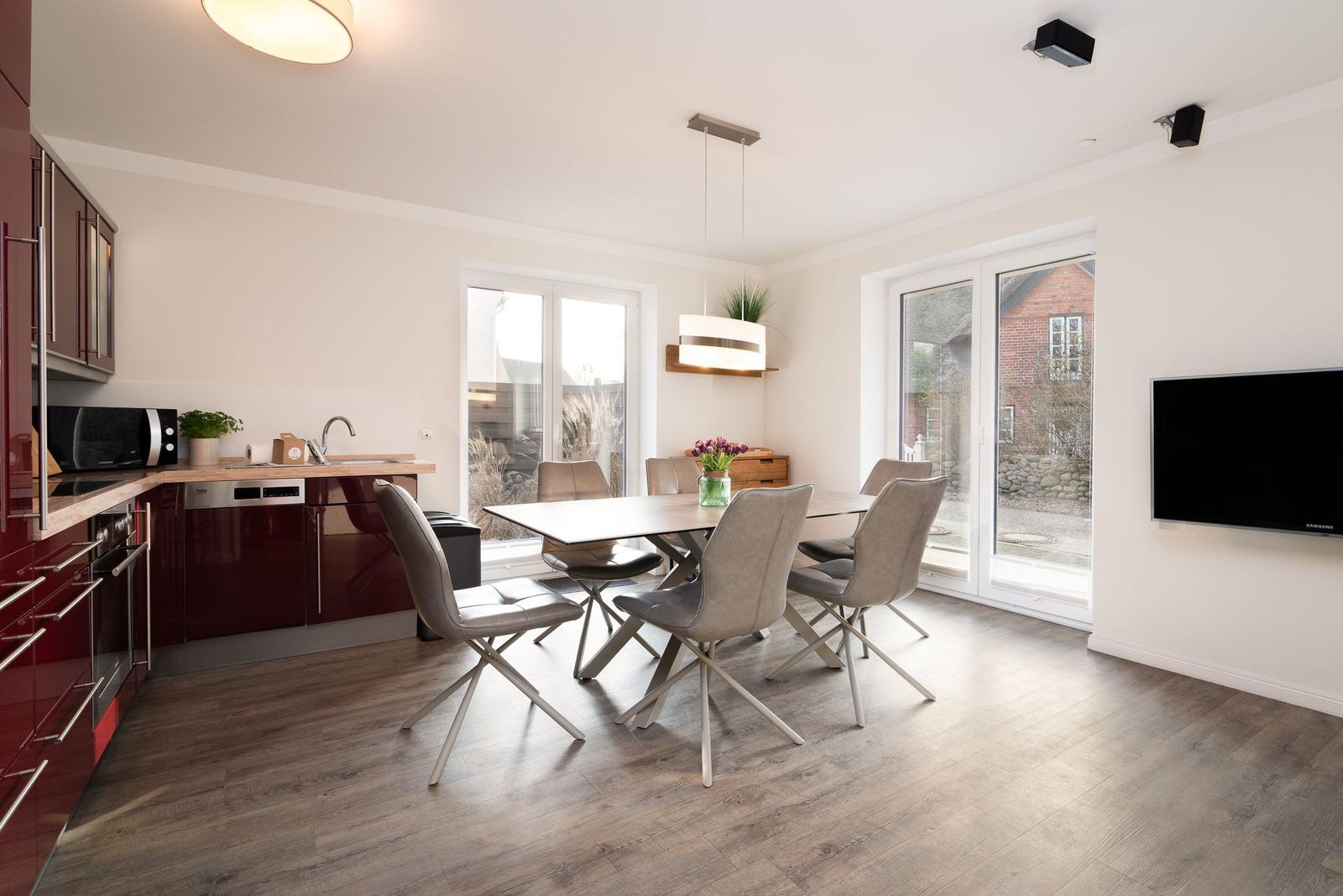 Kitchen with dining area and TV. Wood floor, large windows, modern furnishings.