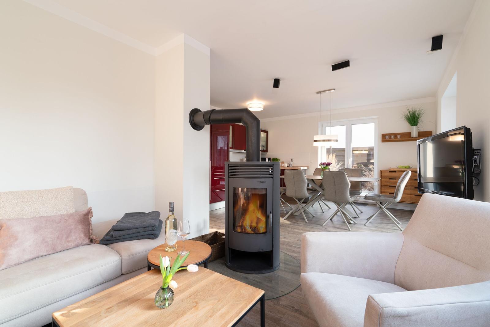 Living area with fireplace, sofa, and dining table. Kitchen in background.