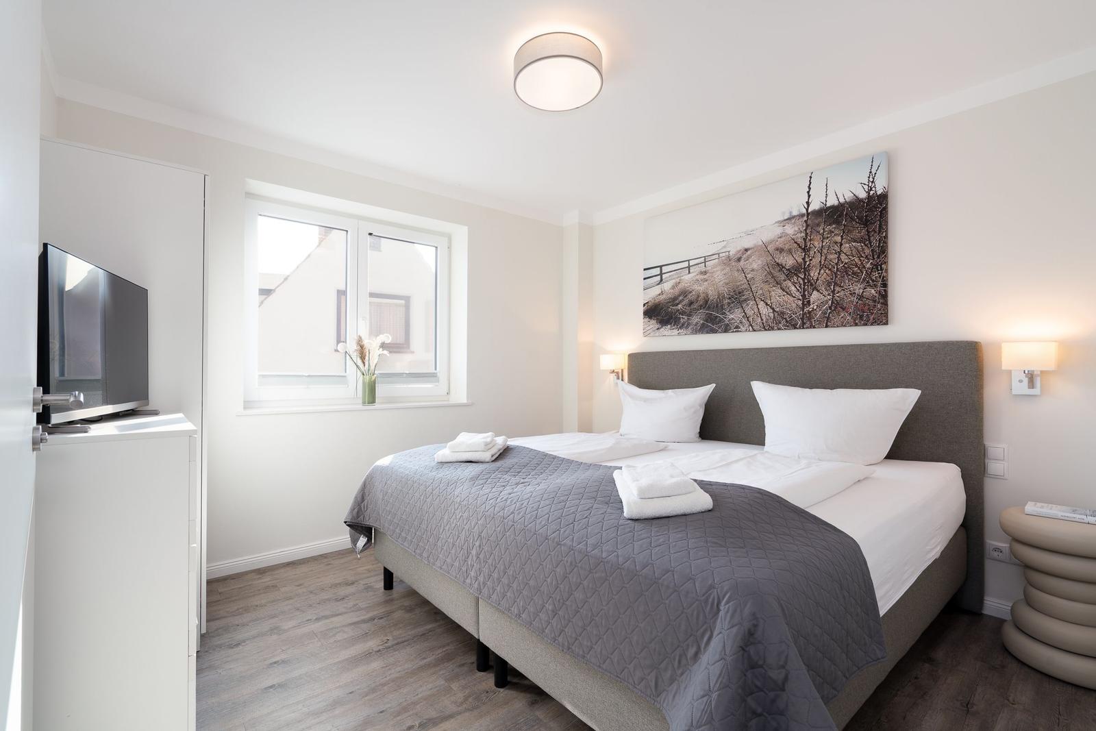 Schlafzimmer mit Doppelbett, Fenster, Wandbild und TV