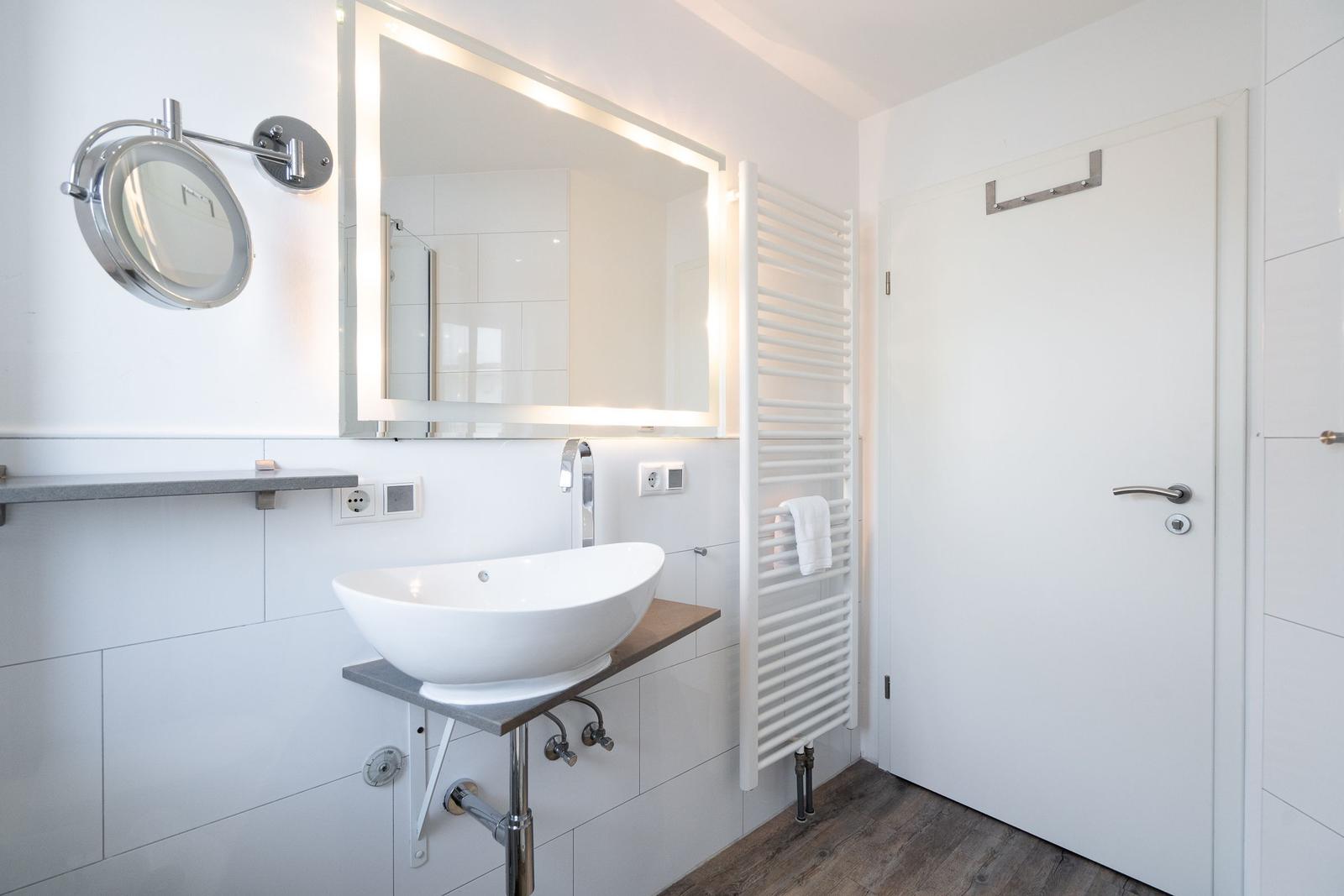 Badezimmer mit Waschbecken, Spiegel und Heizkörper