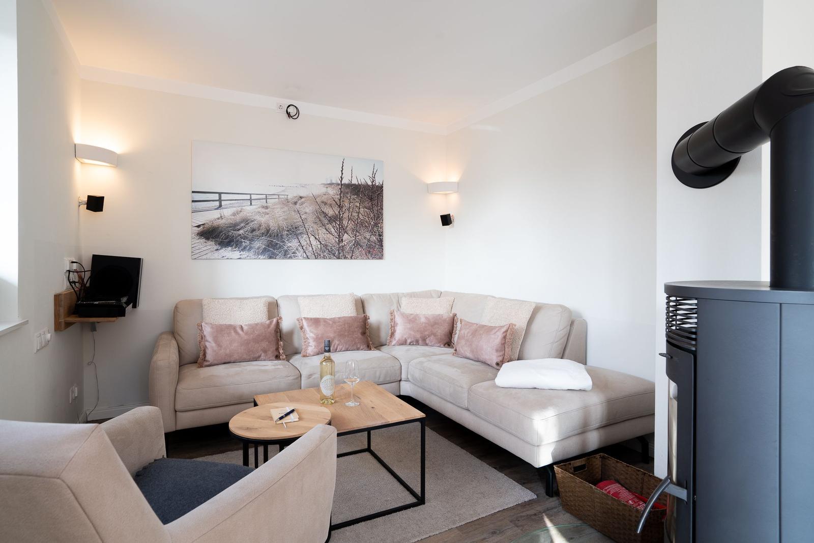 Wohnzimmer mit Sofa, Couchtisch und Kaminofen. Wandbild und Wandlampen sichtbar.