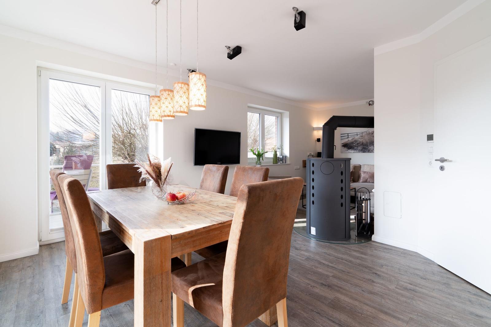 Esszimmer mit Holztisch, braunen Stühlen und Fenster zur Terrasse.