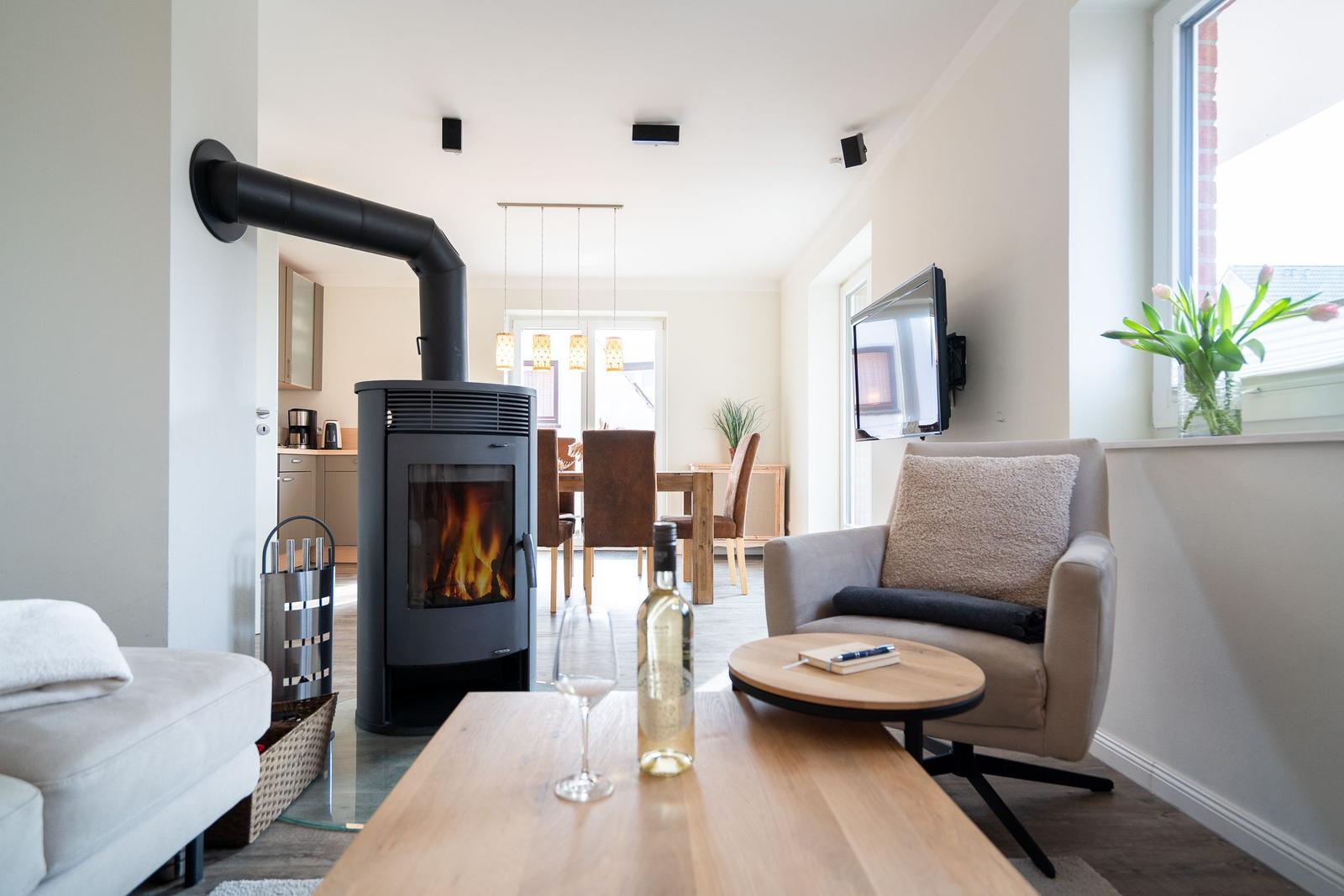 Wohnzimmer mit Kaminofen, Sitzgelegenheiten und Fernseher an der Wand.
