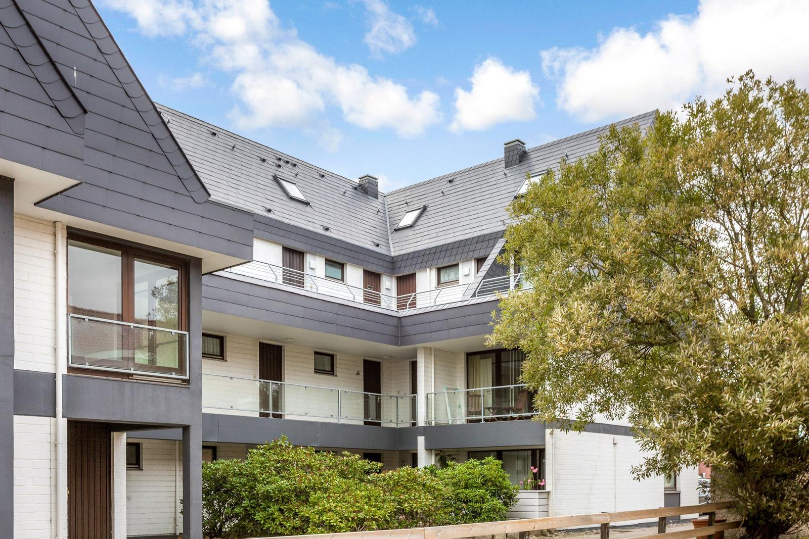 Moderne Wohnung mit Balkon, Dachfenstern und grüner Umgebung.