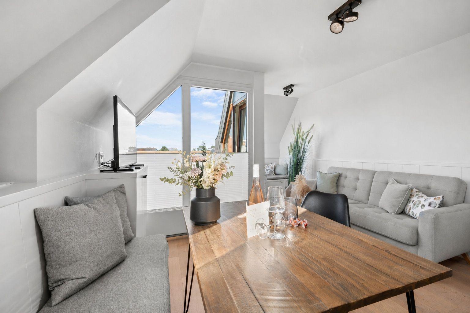Wohnzimmer mit Sofa, Esstisch und TV unter Dachschrägen.