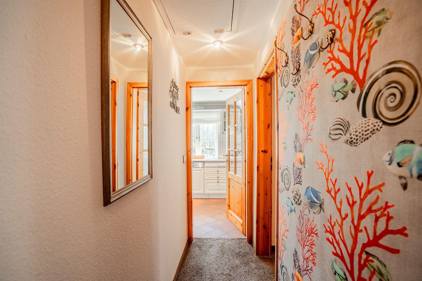 Flur mit Meerestier-Wandtapete und Spiegel an der Wand.