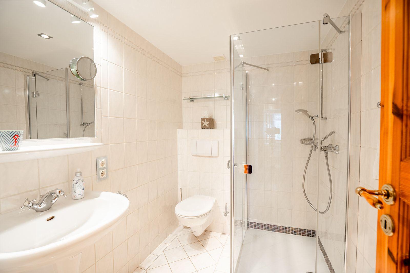 Badezimmer mit Dusche, Toilette und Waschbecken.