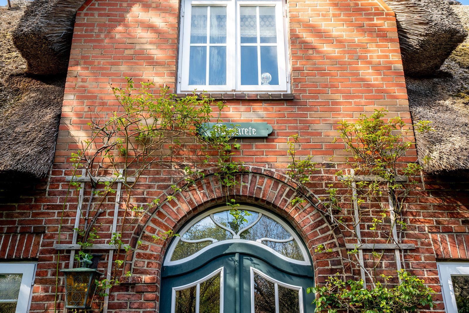 Haus mit rotem Backstein, grüner Tür und strohgedecktem Dach