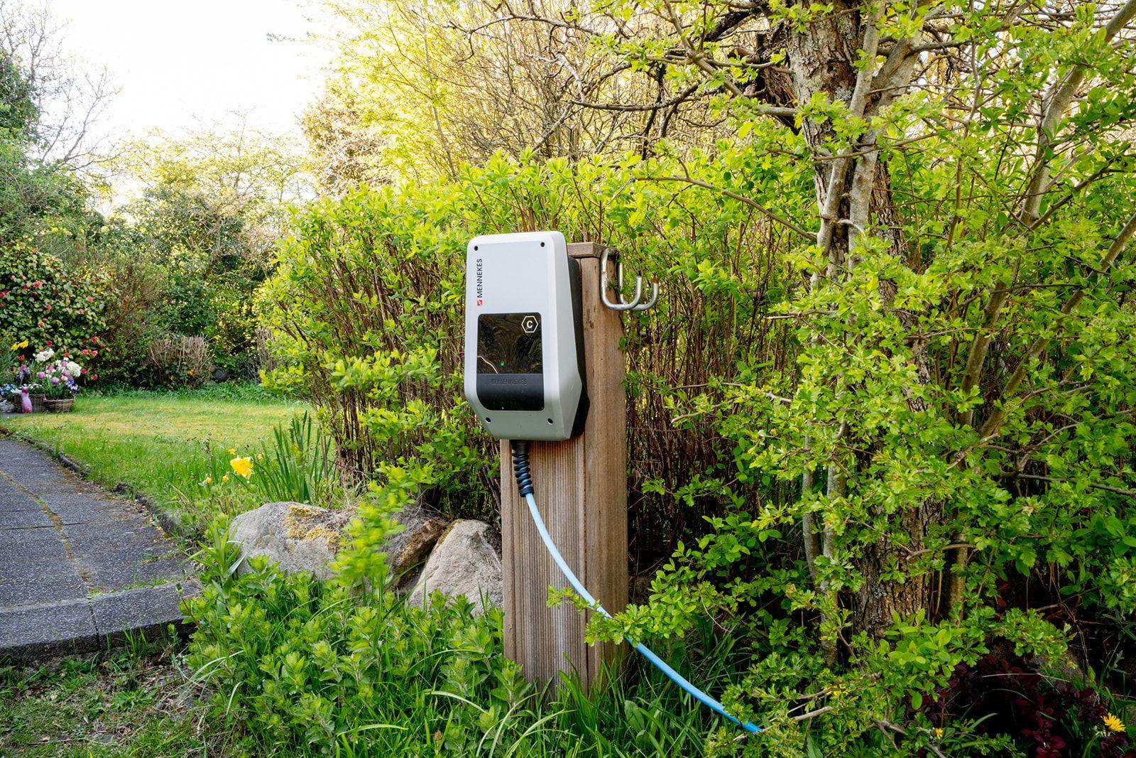 Ladestation im Garten an Holzpfosten mit Kabel und Grünflächen