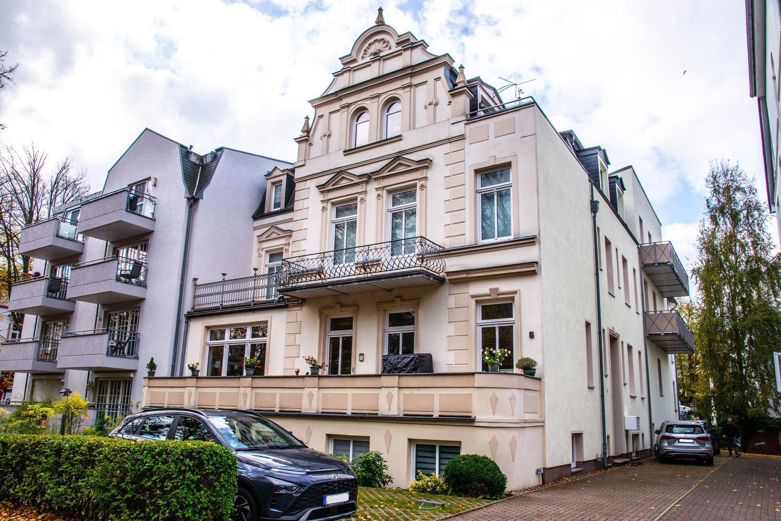 Historisches Gebäude mit Balkonen und Fenstern. Autos parken vor dem Haus.