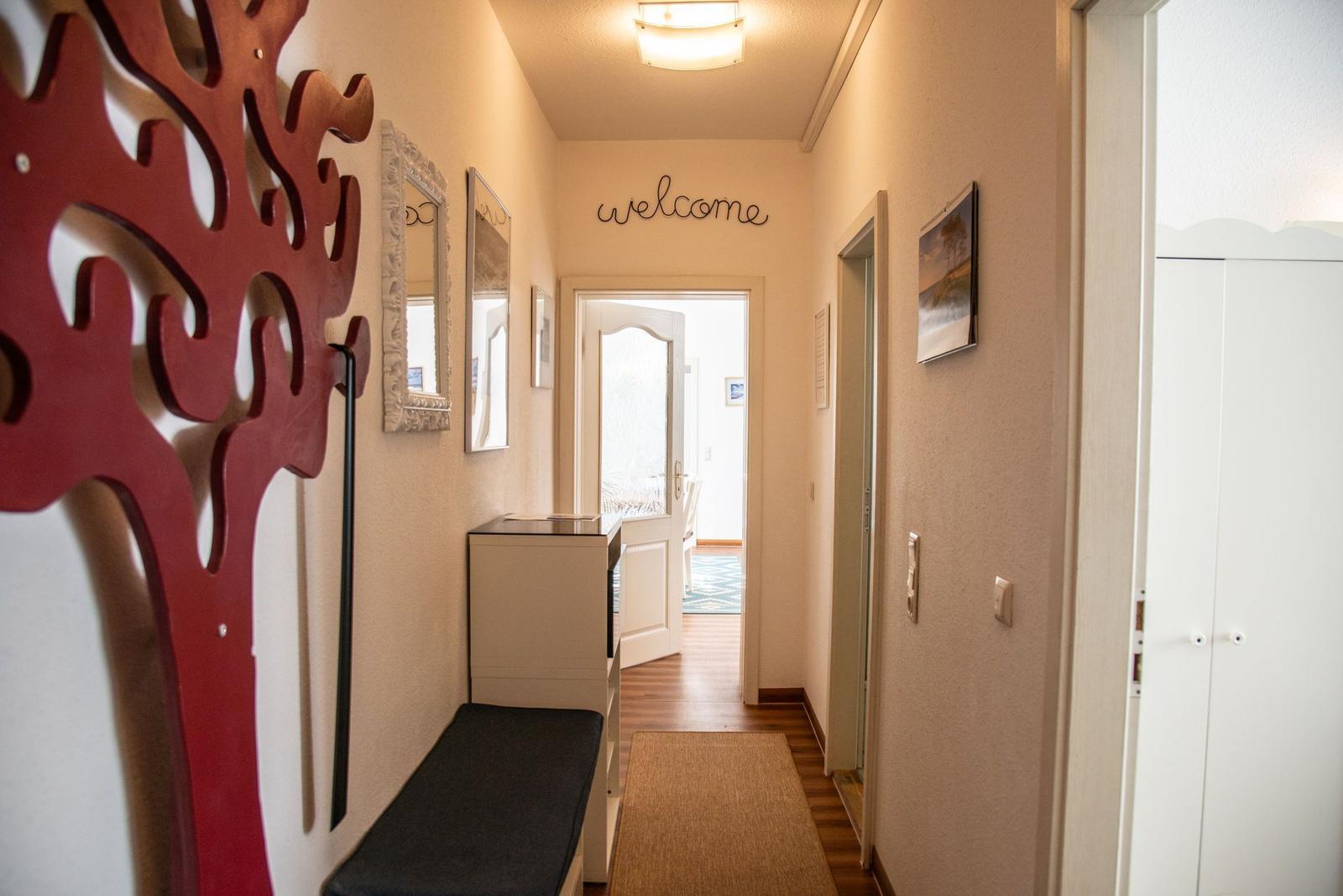 Hausflur mit rotem Baumdekoration, Spiegel und welcome-Schild.