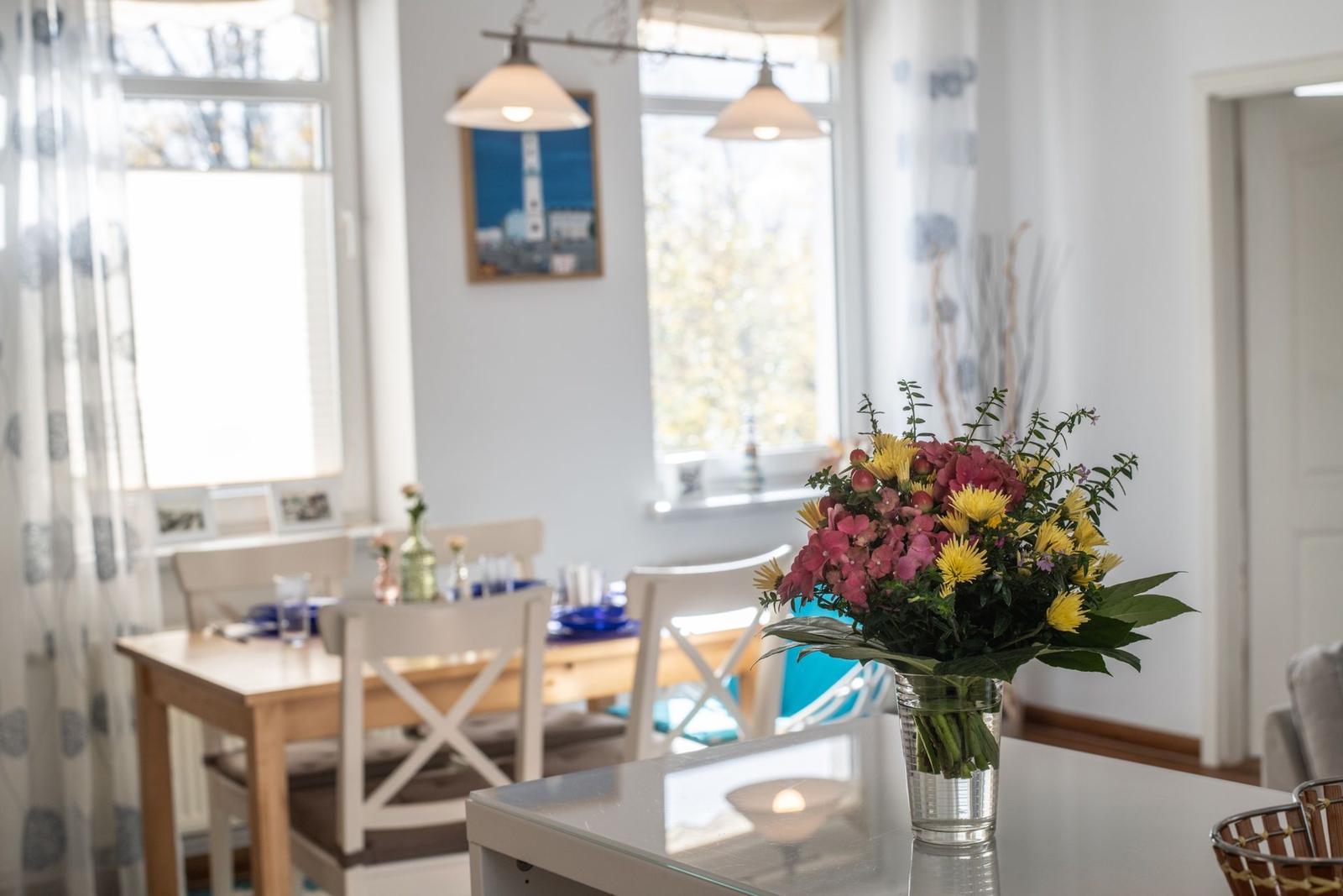 Ein Essbereich mit Tisch, Stühlen und Blumenarrangement auf der Arbeitsplatte.