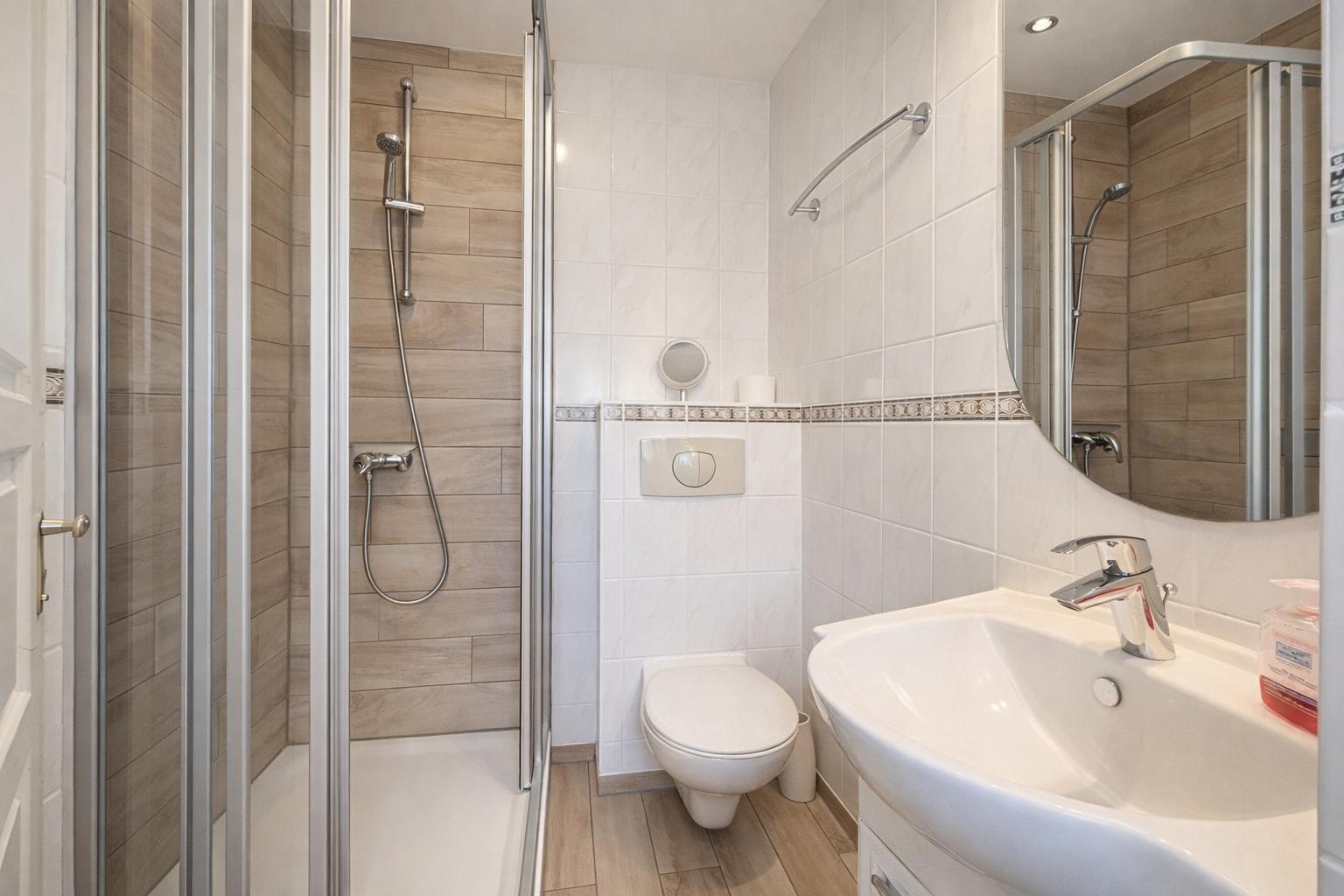 Badezimmer mit Dusche, Toilette und Waschbecken.