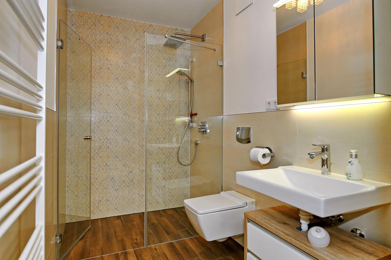 Badezimmer mit Dusche, Waschbecken und Toilette.