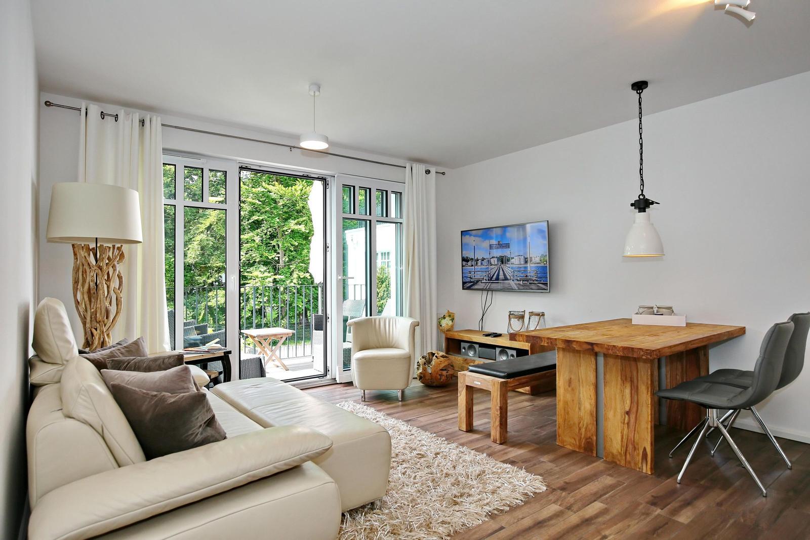 Wohn- und Essbereich mit Sofa, Esstisch und TV. Durchgang zur Terrasse mit Gartenblick.