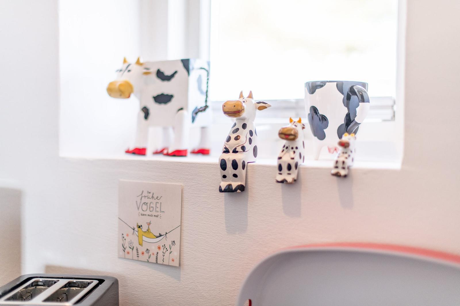 Kitchen window with cow figurines and wall decoration.