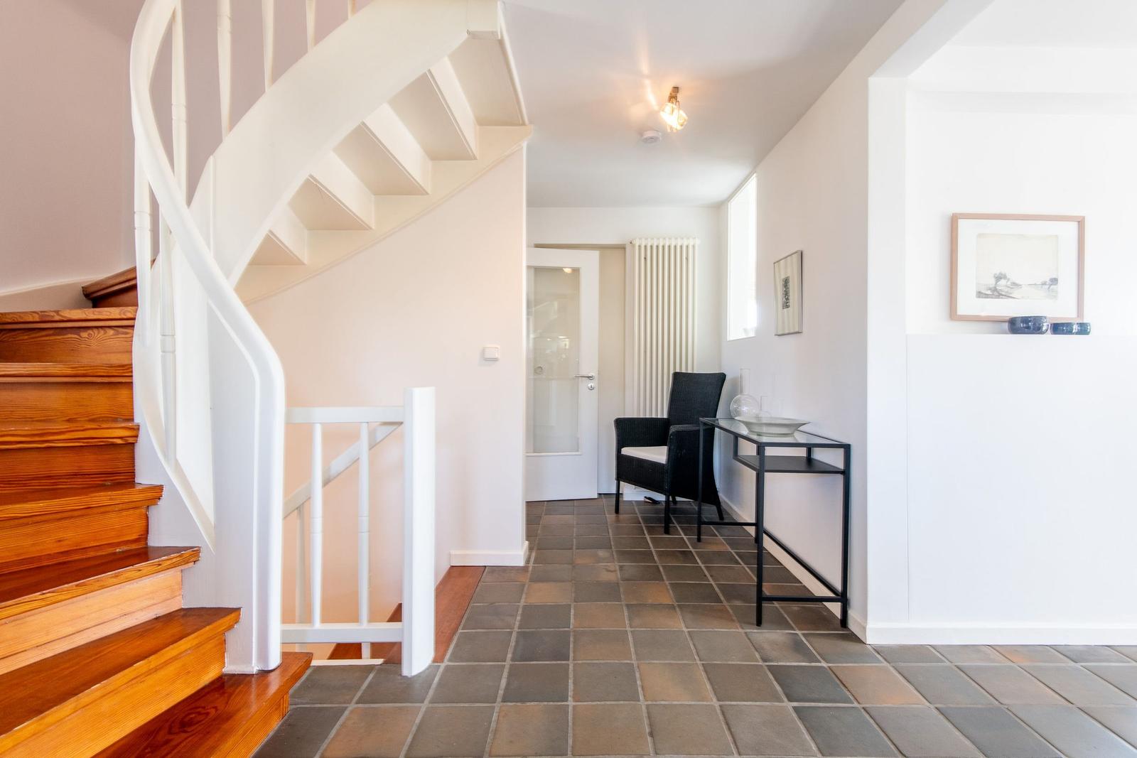 House with staircase, seating area, and table in hallway.