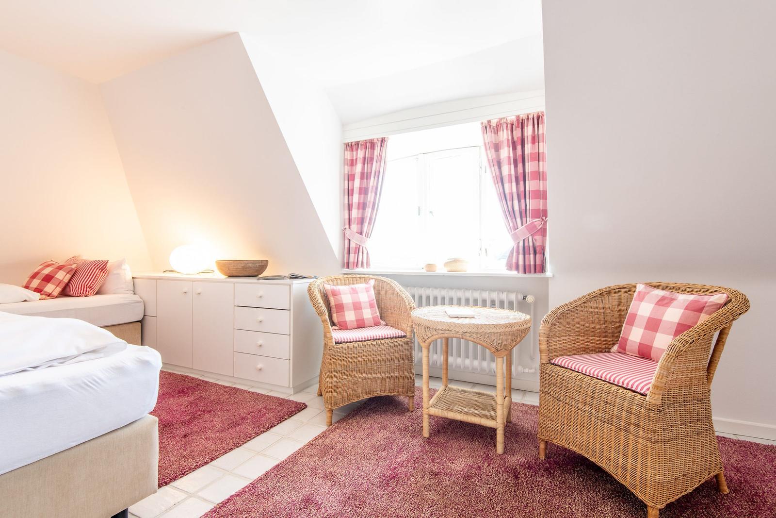 Bedroom with two chairs, table, and window with curtains.