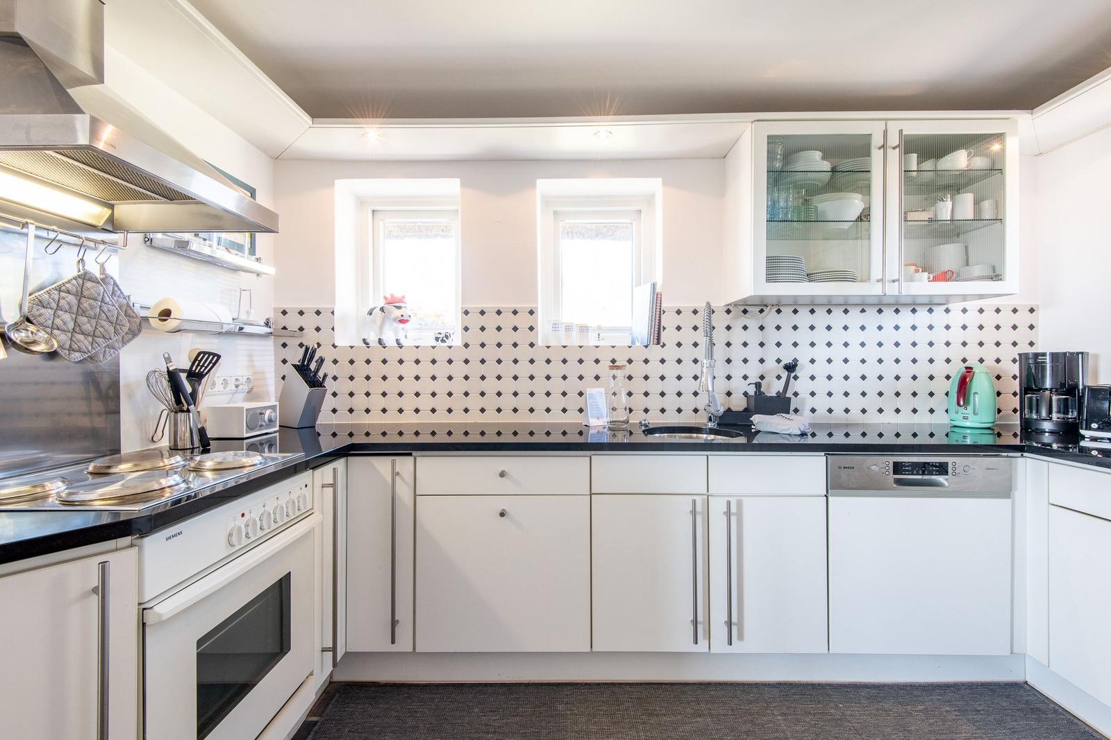 Kitchen with white cabinets, black countertop, and two windows.