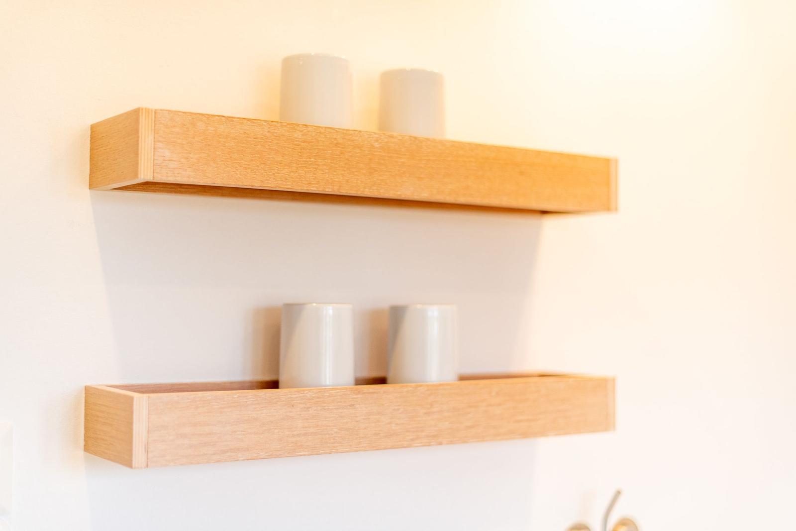 Two wooden shelves on the wall with white cylinders.