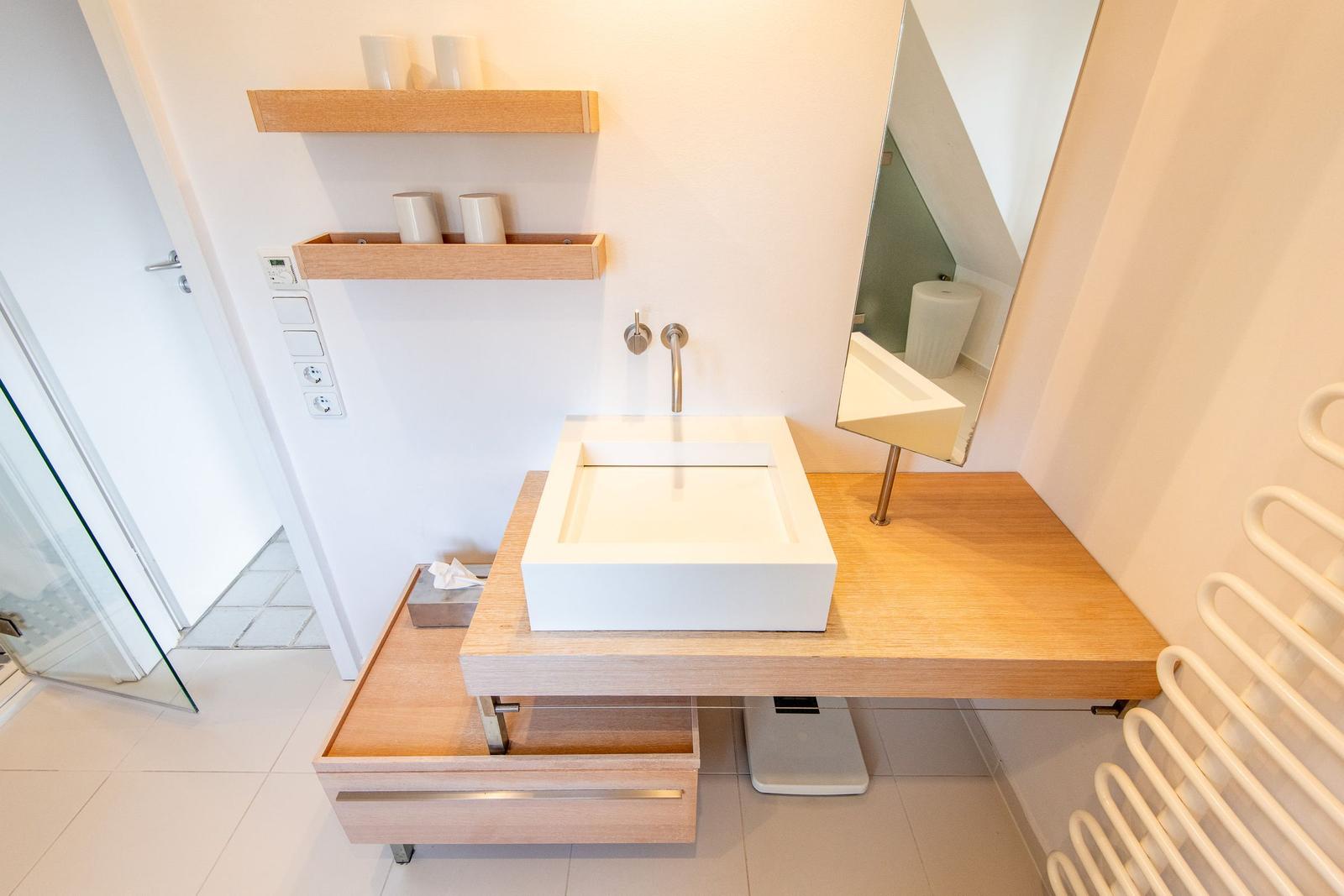 Sink on wooden vanity with mirror and shelf