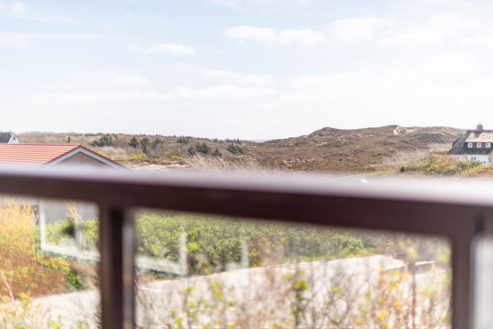 View from balcony over hills with grass and houses in the background.