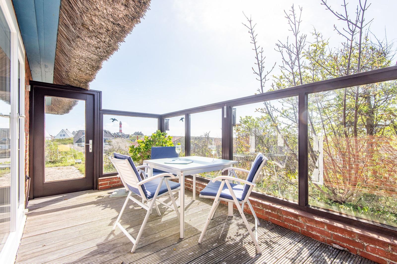 Terrace with table and chairs, view of lighthouse and greenery.