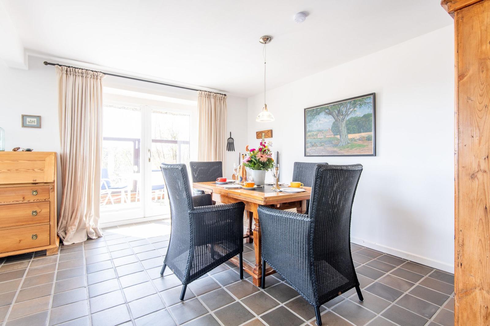 Dining room with wooden table, four chairs, and view to terrace.